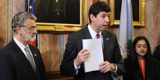 U.S. Attorney Steven Dettelbach, center, holds up the settlement agreement with the City of Cleveland as he speaks at a news conference Tuesday, May 26, 2015, in Cleveland. 