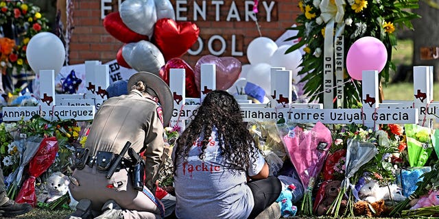 A police officer comforts family members at a memorial outside Robb Elementary School in Uvalde, Texas on May 26.