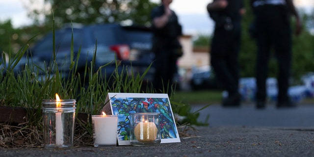 Police walk by a small memorial as they investigate after a shooting at a supermarket on Saturday, May 14, 2022, in Buffalo, N.Y. (AP Photo/Joshua Bessex)