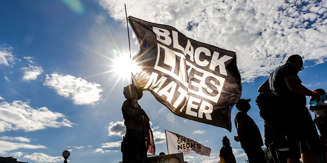 A woman holds a Black Lives Matter flag during an event in remembrance of George Floyd and to call for justice for those who lost loved ones to the police violence outside the Minnesota State Capitol on May 24, 2021 in Saint Paul, Minnesota.
