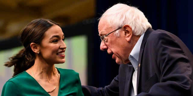 Rep. Alexandria Ocasio-Cortez is joined on stage by Democratic presidential candidate Bernie Sanders during the climate crisis summit at Drake University on Nov. 9, 2019, in Des Moines, Iowa.