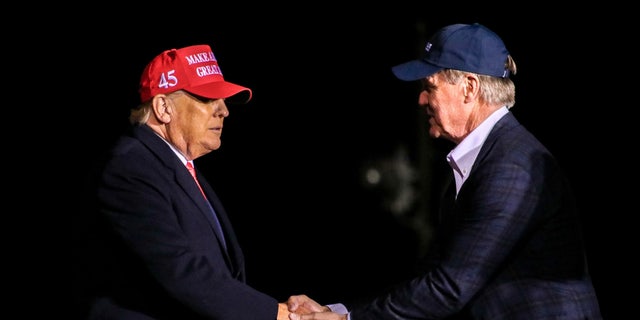 Donald Trump shakes hands with former Sen. David Perdue, who primary challenged GOP Gov. Brian Kemp, at the former president's rally in Cumming, Georgia, on March 26, 2022.