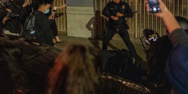 A police officer is surrounded by a group of demonstrators near Pershing Square following a protest outside of the U.S. Courthouse in response to leaked draft of the Supreme Court's opinion to overturn Roe v. Wade, in Los Angeles, Tuesday, May 3, 2022. (AP Photo/Ringo H.W. Chiu)