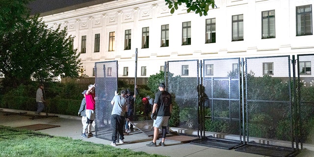 Workers assemble non-scalable fences around the Supreme Court Building amid ongoing abortion-rights demonstrations on May 4, 2022, in Washington, D.C.