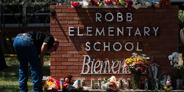 A law enforcement personnel lights a candle outside Robb Elementary School in Uvalde, Texas, Wednesday, May 25, 2022.