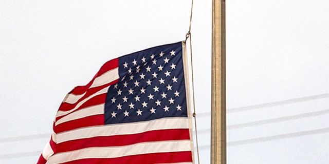 Janish Patel lowers the flag to half staff Tuesday, May 24, 2022, at his Uvalde, Texas, hotel hours after a gunman entered Robb Elementary School in Uvalde and killed multiple children and adults. (William Luther/The San Antonio Express-News via AP)