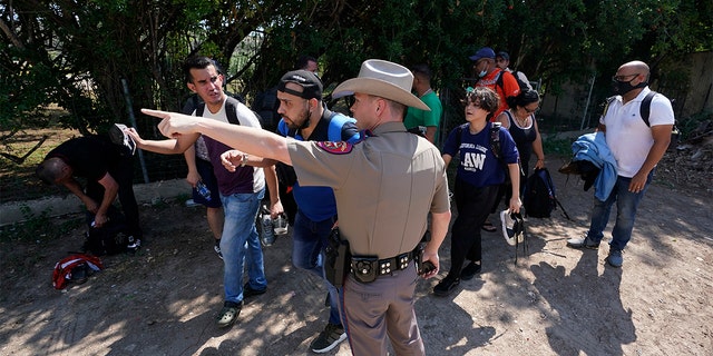 FILE - In this Wednesday, June 16, 2021 file photo, A Texas Department of Public Safety officer in Del Rio, Texas directs a group of migrants who crossed the border and turned themselves in. (AP Photo/Eric Gay, File)