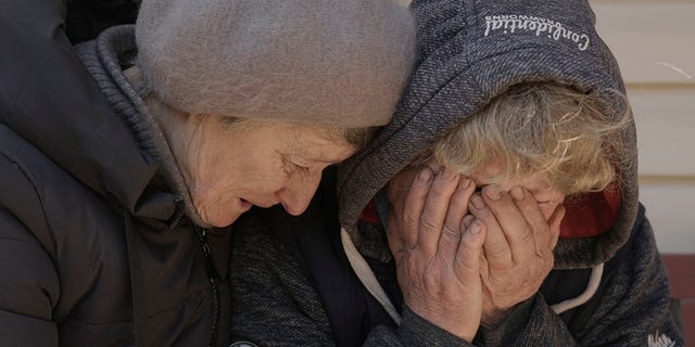 A neighbor comforts Natalya, whose husband and nephew were killed by Russian forces, as she cries in her garden in Bucha, Ukraine, April 4, 2022. 