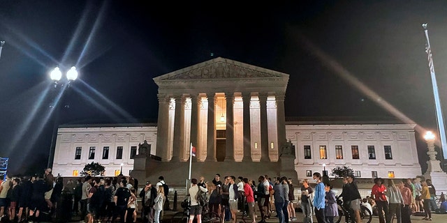 A crowd of people gather outside the Supreme Court, Monday night, May 2, 2022 in Washington. A draft opinion circulated among Supreme Court justices suggests that earlier this year a majority of them had thrown support behind overturning the 1973 case Roe v. Wade that legalized abortion nationwide, according to a report published Monday night in Politico. It’s unclear if the draft represents the court’s final word on the matter.  The Associated Press could not immediately confirm the authenticity of the draft Politico posted, which if verified marks a shocking revelation of the high court’s secretive deliberation process, particularly before a case is formally decided. (AP Photo/Anna Johnson)