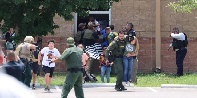 Children run to safety after escaping from a window during a mass shooting at Robb Elementary School where a gunman killed nineteen children and two adults in Uvalde, Texas, U.S. May 24, 2022. 