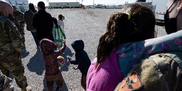 Nov 4., 2021 Children play with a ball as they walk with a group of media and military service members in an Afghan refugee camp in Holloman Air Force Base, New Mexico. (Photo by Jon Cherry/Getty Images)
