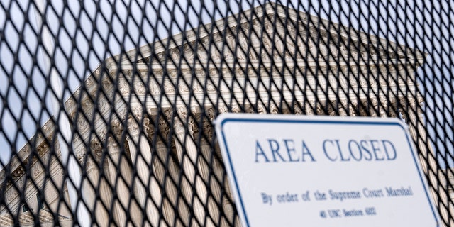 The U.S. Supreme Court is seen through a fence with a "Closed Area" sign in Washington, May 11, 2022.