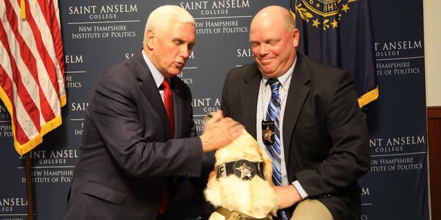 Former Vice President Mike Pence pets a police dog that was born in Pence's home state of Indiana during a roundtable discussion the former vice president had with law enforcement members May 26, 2022, at the New Hampshire Institute of Politics in Goffstown, N.H.