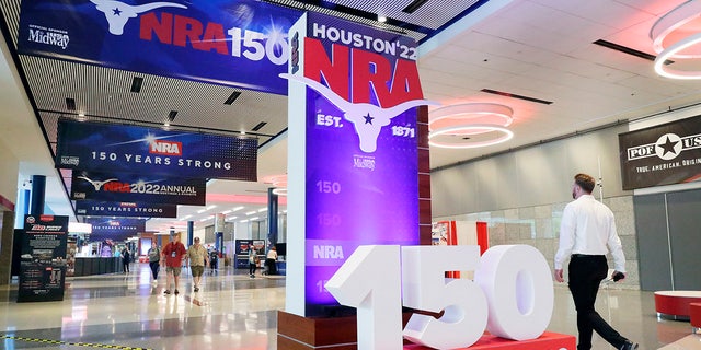People walk past signage in the hallways outside of the exhibit halls at the NRA Annual Meeting held at the George R. Brown Convention Center Thursday, May 26, 2022, in Houston. (AP Photo/Michael Wyke)