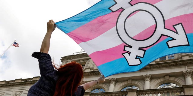 A person holds up a flag during rally to protest the Trump administration's reported transgender proposal to narrow the definition of gender to male or female at birth, at City Hall in New York City, U.S., Oct. 24, 2018.