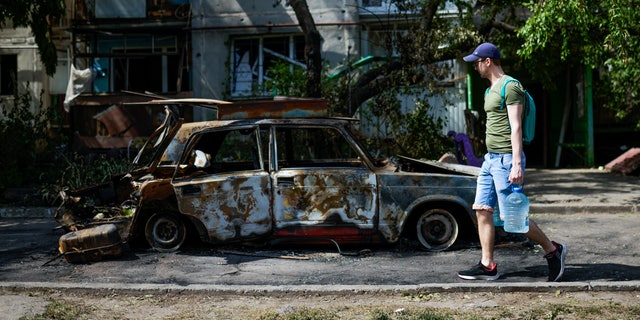 A man carries water in front of an apartment building damaged in an overnight missile strike, in Sloviansk, Ukraine, May 31, 2022.