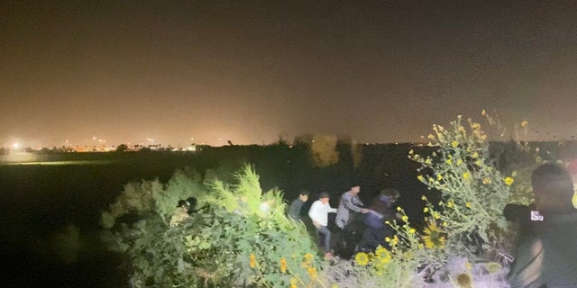 A group of migrants is led out of the brush and to a main road near Hidalgo, Texas, by Texas National Guardsmen. 