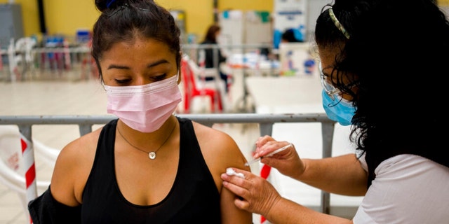 A healthcare worker administers a booster dose of a COVID 19 vaccine at a temporary vaccine center in Guatemala City, Tuesday, March 1, 2022. 