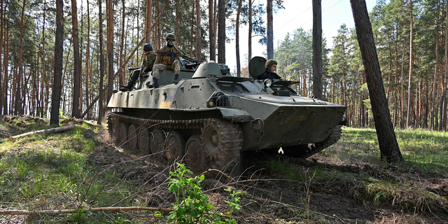 Ukrainian soldiers are seen riding on an armored personnel carrier during an exercise not far from Kharkiv on April 30.