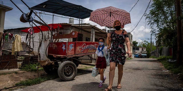Danmara Triana walks home after picking up her daughter Alice from school in Cienfuegos, Cuba, Thursday, May 19, 2022. Triana's husband and son, who is Alice's father and brother, have lived in the U.S. since 2015, while she and their two daughters stayed behind. (AP Photo/Ramon Espinosa)