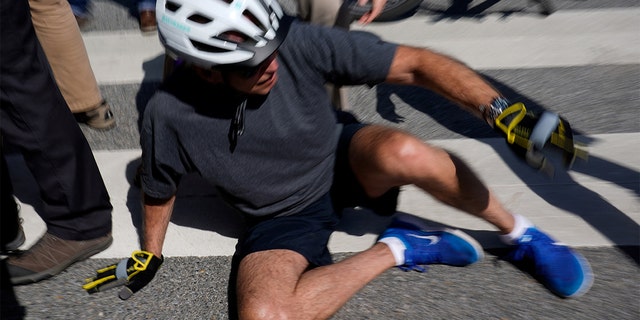 President Biden falls to the ground after riding up to members of the public during a bike ride in Rehoboth Beach, Delaware, June 18, 2022. 