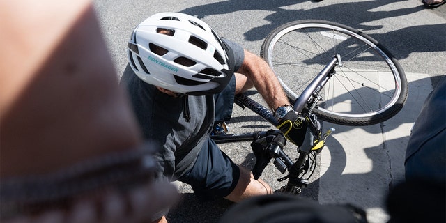 President Biden falls off his bicycle as he approaches well-wishers following a bike ride at Gordon's Pond State Park in Rehoboth Beach, Delaware, on June 18, 2022. 