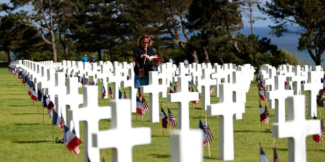 A woman holds a bouquet of roses during the 78th anniversary of D-Day ceremony, in the Normandy American Cemetery and Memorial of Colleville-sur-Mer, overlooking Omaha Beach, Monday, June, 6, 2022.