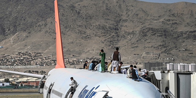 Aug 16, 2021: Afghan people climb atop a plane as they wait at the Kabul airport in Kabul.