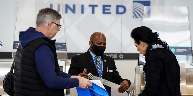 FILE: A United Airlines worker assists travelers after the Biden administration announced it would no longer enforce a U.S. coronavirus disease (COVID-19) mask mandate on public transportation, at Ronald Reagan Washington National Airport in Arlington, Virginia, U.S.