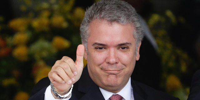 FILE - In this Sept. 10, 2018 file photo, Colombia's President Ivan Duque gives a thumbs up to the press during a welcoming ceremony for him at the presidential palace in Panama City. As Duque completes his first 100 days in office, his administration has been beset by street protests and an unruly congress that has blocked some of his flagship initiatives. (AP Photo/Arnulfo Franco, File)