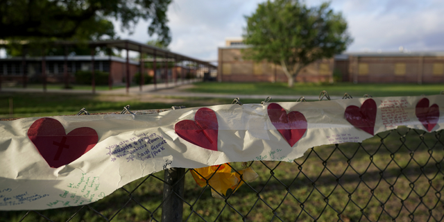 Hearts on a banner hang on a fence at a boarded up Robb Elementary School on Friday, June 3.