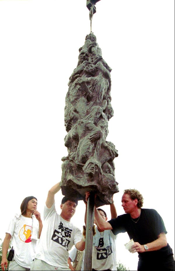 FILE - In this June 3, 1997, file photo, Danish artist Jens Galschiot, right, supervises erection of the "Pillar of Shame," a bronze statue to mark the military crackdown of a pro-democracy student movement in Beijing in June, 1989, at Hong Kong's Victoria Park. Galschioet is seeking to get back his sculpture in Hong Kong memorializing the victims of China's 1989 Tiananmen Square crackdown as a deadline loomed for its removal Wednesday, Oct. 13, 2021. (AP Photo/Vincent Yu, File)