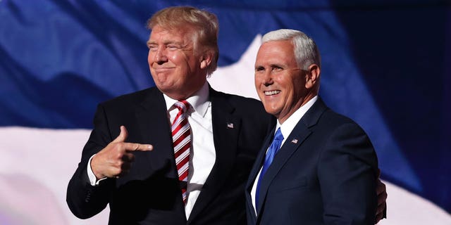 Donald Trump and Mike Pence pose together on stage. 