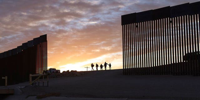 A pair of migrant families from Brazil pass through a gap in the border wall to reach the United States after crossing from Mexico to Yuma, Ariz., to seek asylum.