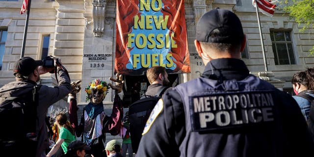 An environmental activist with the group Extinction Rebellion DC scales a building on April 22, in Washington, D.C. (Photo by Kevin Dietsch/Getty Images)