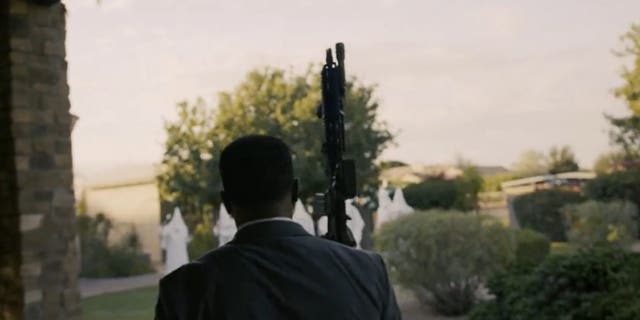 Republican candidate Jerone Davison brandishes rifle against people dressed in white hoods in campaign ad