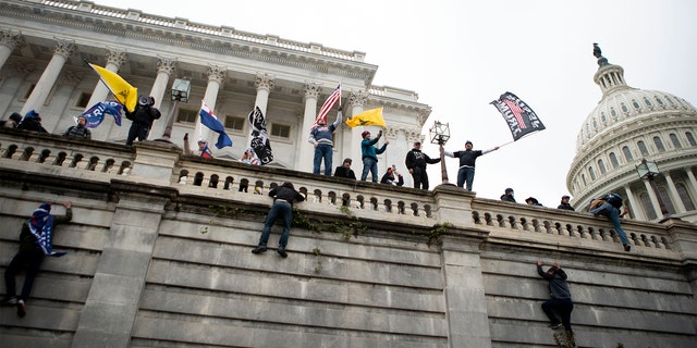 Supporters of President Donald Trump climb the west wall of the the U.S. Capitol on Wednesday, Jan. 6, 2021, in Washington.