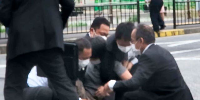 In this image from a video, a man, center, is detained near the site of gunshots in Nara, western Japan. Japan's former Prime Minister Shinzo Abe was shot and died later after giving a campaign speech in Nara. 