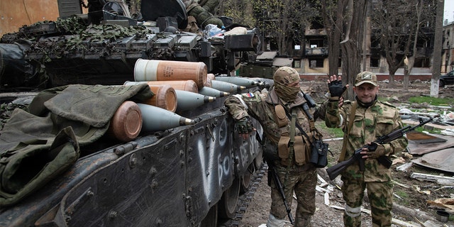 Russian soldiers pose near a T-80 tank in a position close to the Azovstal frontline in the besieged port city of Mariupol. 