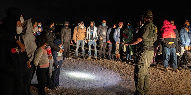 A U.S. Border Patrol agent speaks with immigrants before transporting some of them to a processing center on December 09, 2021 in Yuma, Arizona.  (Photo by John Moore/Getty Images)
