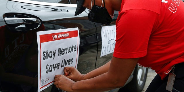 A woman puts a sign on her car prior to the Occupy City Hall Protest and Car Caravan hosted by Chicago Teachers Union in Chicago, Illinois, on August 3, 2020.
