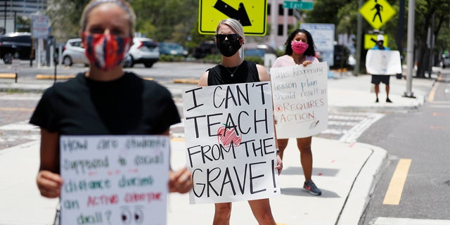 Middle school teacher Brittany Myers, center, stands in protest in front of the Hillsborough County school district office on July 16, 2020, in Tampa, Florida.