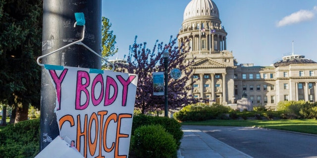 FILE - A sign reading "My body, my Choice," is taped to a hanger taped to a streetlight in front of the Idaho State Capitol Building on May 3, 2022.