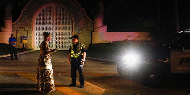 A police officer speaks with a woman outside former U.S. President Donald Trump's Mar-a-Lago home after Trump said that FBI agents raided it, in Palm Beach, Florida, U.S., August 8, 2022. 