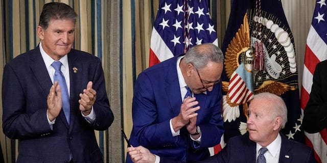 President Joe Biden, right, moves to give Sen. Joe Manchin, D-W.Va., left, the pen he used to sign the Inflation Reduction Act with Senate Majority Leader Charles Schumer, D-N.Y., at the White House on Aug. 16, 2022.