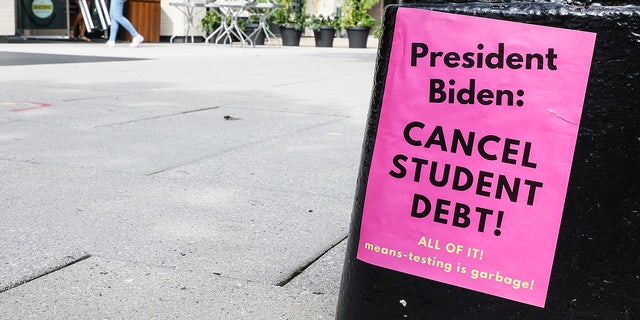 A sign asking President Biden to cancel student debt is seen posted on Pennsylvania Ave near the White House staff entrance during a demonstration July 27, 2022. 