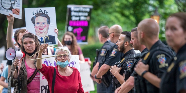  Police officers look on as abortion-rights advocates hold a demonstration outside the home of U.S. Supreme Court Justice Brett Kavanaugh on May 18, 2022 in Chevy Chase, Maryland.