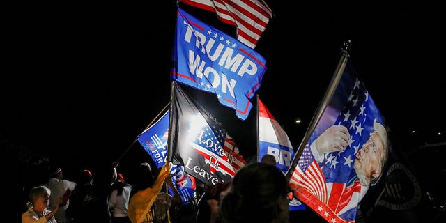 Supporters of former President Donald Trump wave flags as they gather outside his Mar-a-Lago home in Palm Beach, Florida, on Monday, Aug. 8, 2022, after FBI agents raided it.