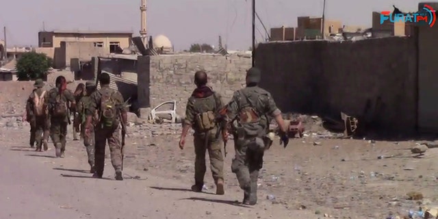 This frame grab from video released Friday, Aug. 11, 2017, and provided by Furat FM, a Syrian Kurdish activist-run media group, shows U.S.-backed Syrian Democratic Forces (SDF) fighters advance in Raqqa, Syria.