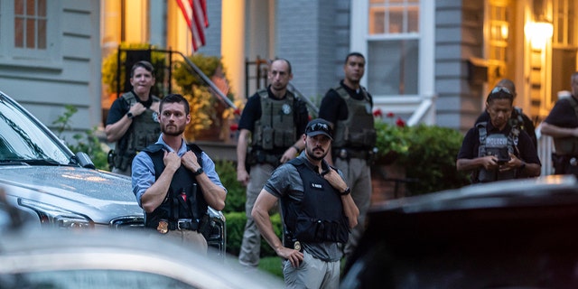 Law enforcement officers stand guard as protesters march past Supreme Court Justice Brett Kavanaugh's home.